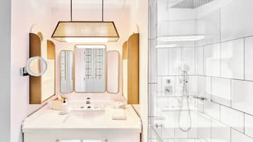 A modern bathroom with a white vanity, a large mirror, and a shower area.