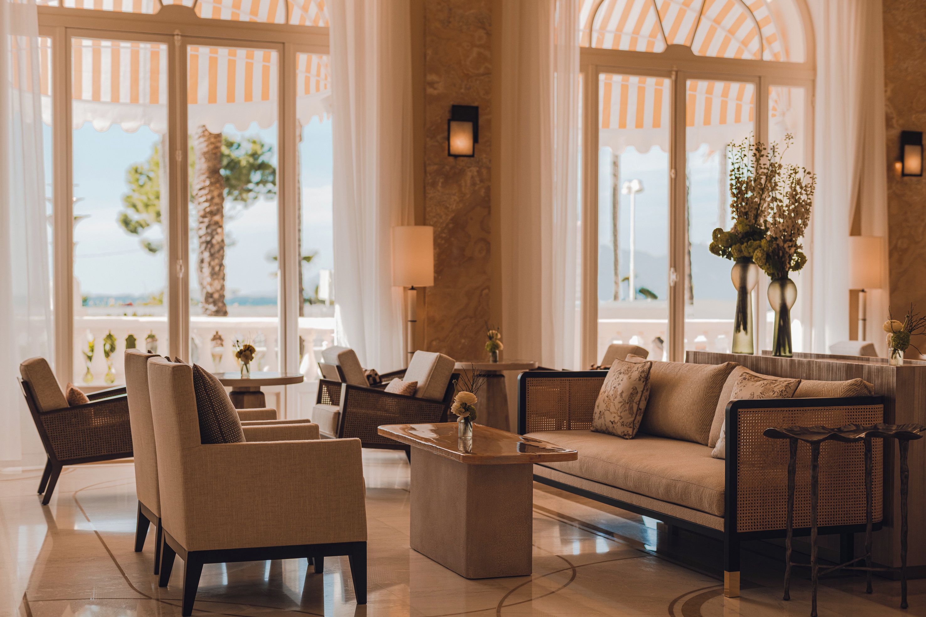 A spacious lobby with a sofa, chairs, a coffee table, and large windows offering a view.