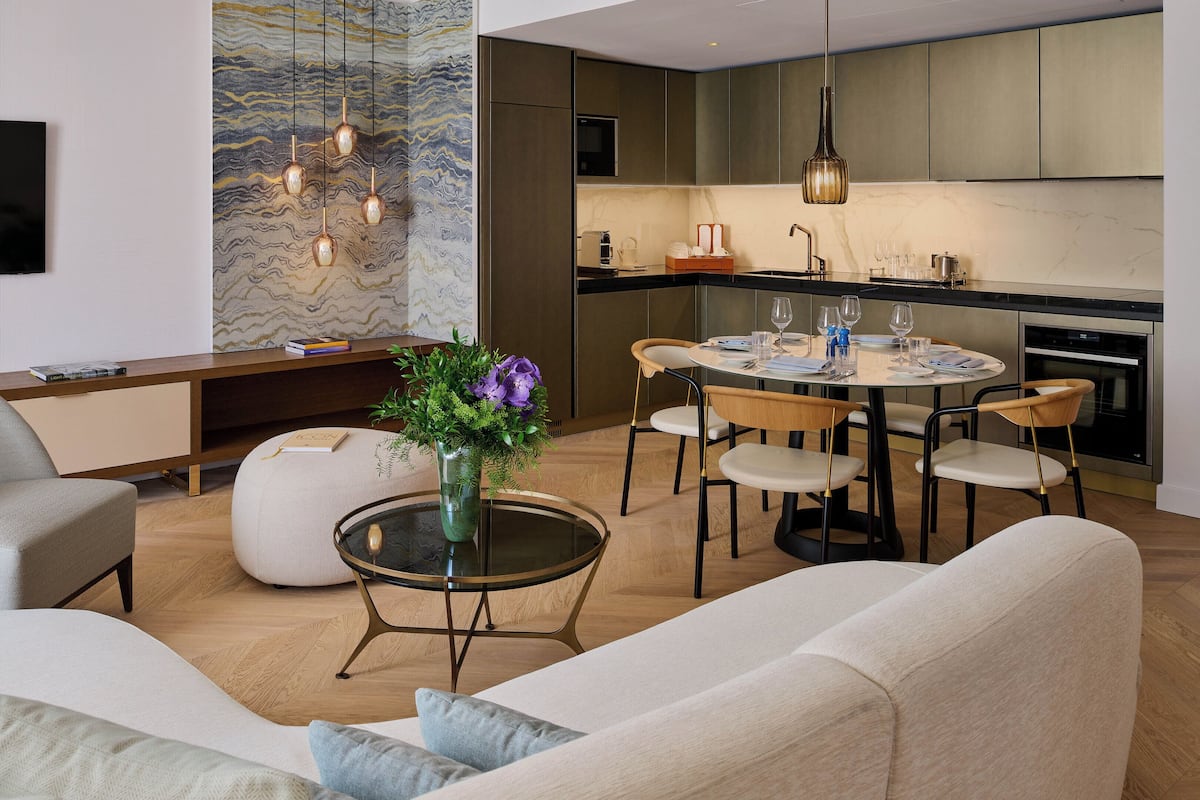 A modern living room with a sofa, a coffee table with a vase of flowers, and a dining area with a round table and chairs.