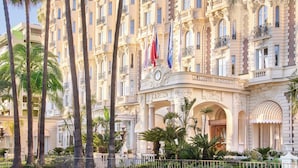 A grand hotel with a classical facade, multiple balconies, and palm trees in the courtyard. - Carlton Cannes, a Regent Hotel (Cannes)