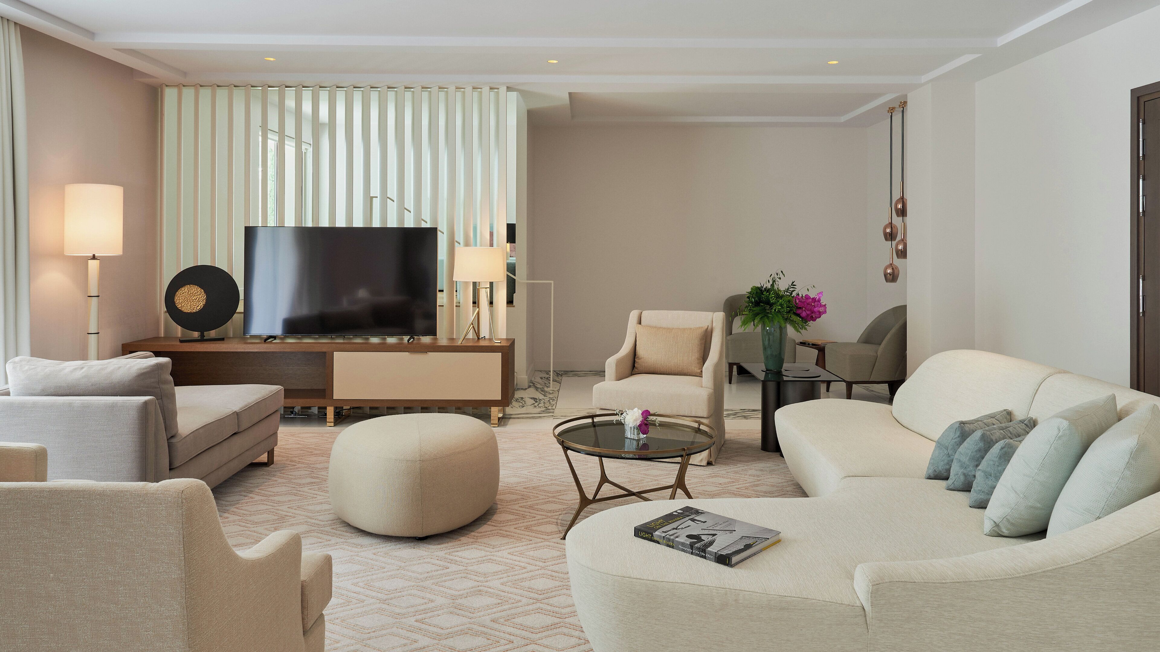 Een moderne woonkamer met een flatscreen televisie, comfortabele zitmogelijkheden en een decoratieve vaas.