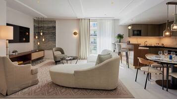 Une chambre d’hôtel moderne dotée d’un espace de vie, d’un coin repas et d’une cuisine.