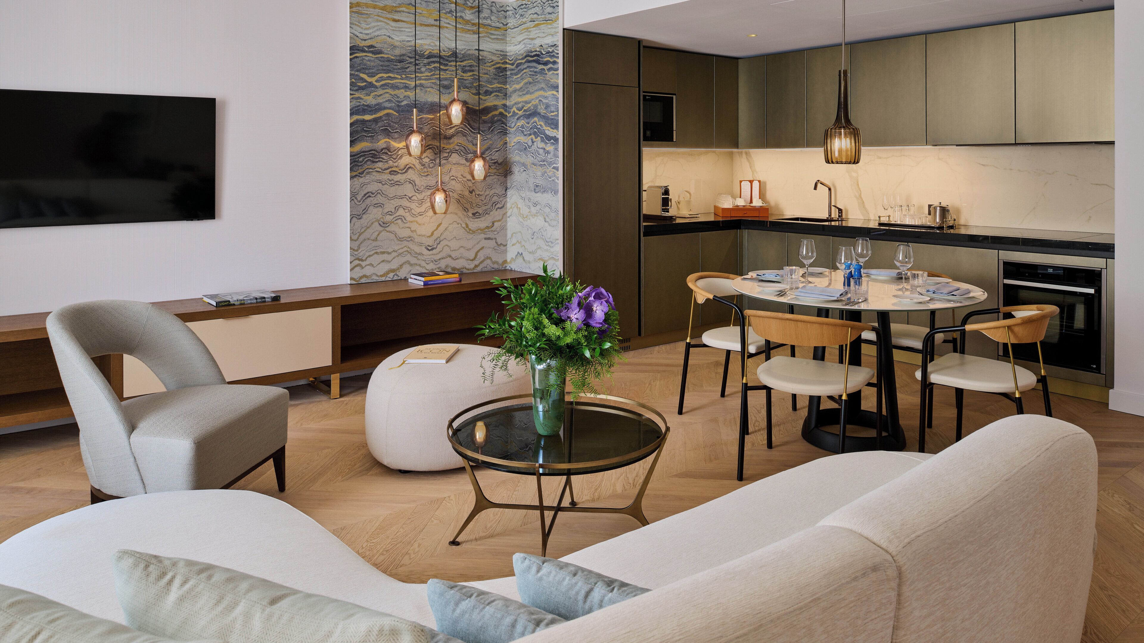 A modern living room with a sofa, a coffee table with a vase of flowers, and a dining area with a round table and chairs.