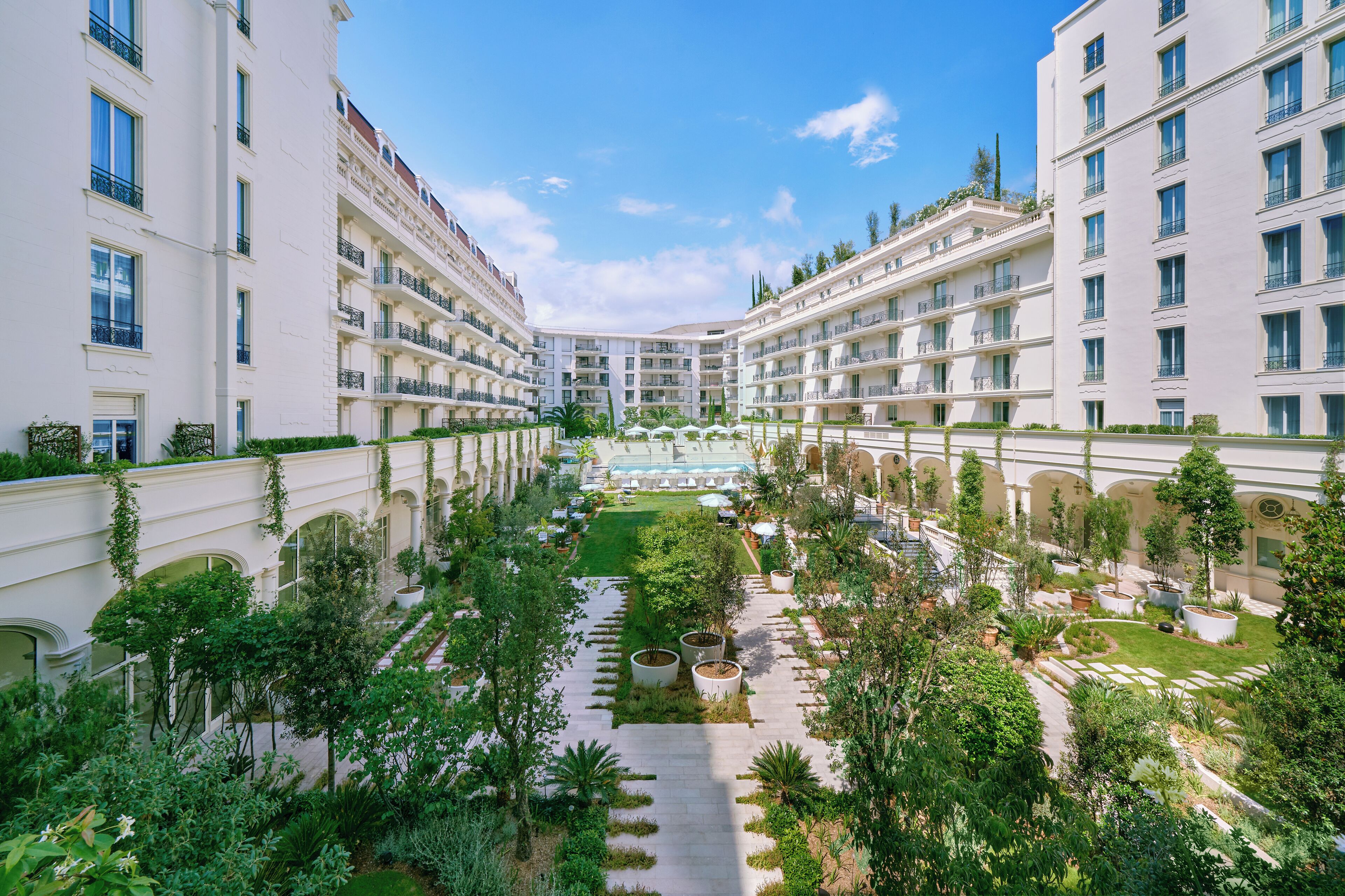 Un patio de hotel con varios balcones, abundante vegetación y un espacio abierto central.