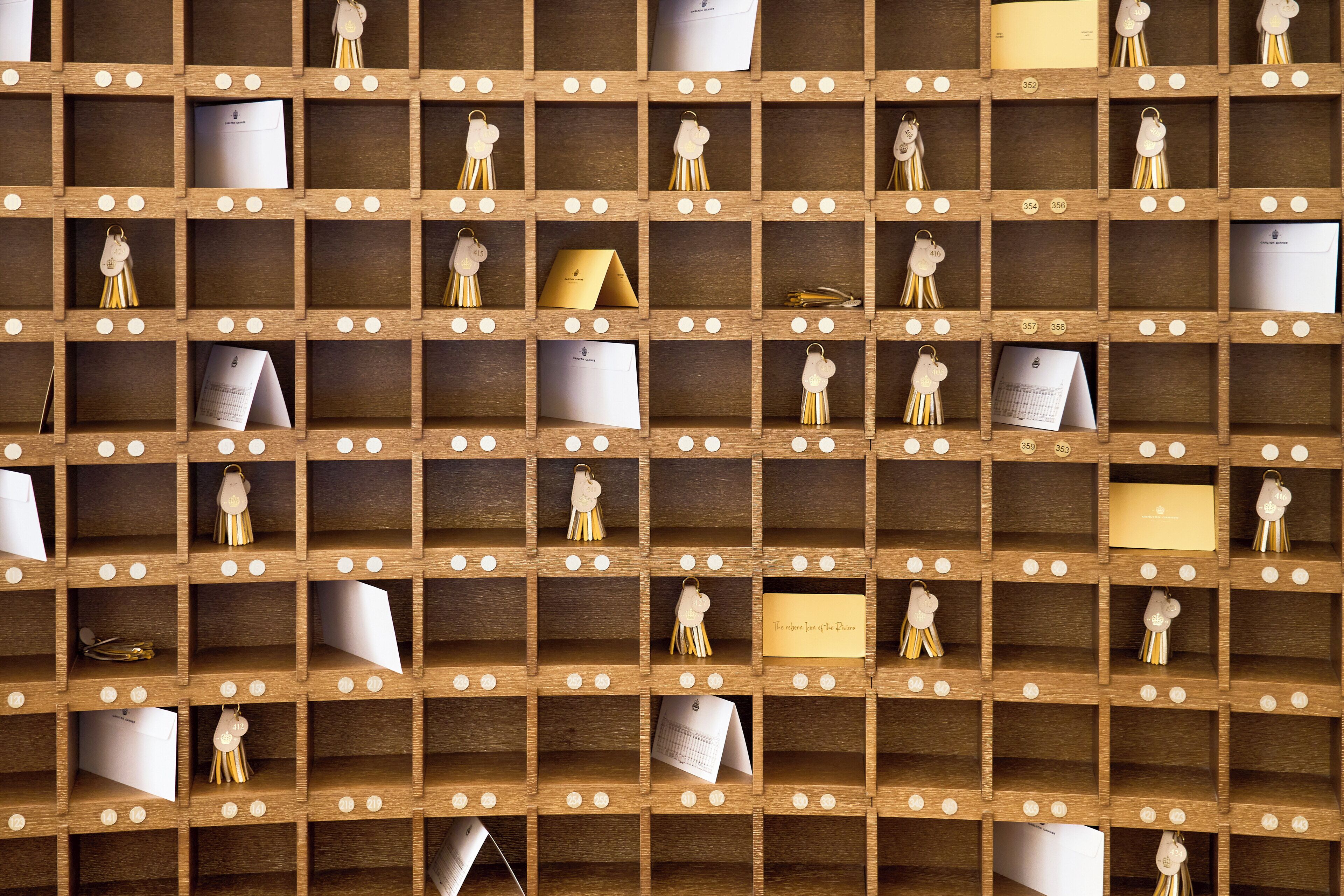 A wooden wall with multiple small compartments, each containing various items like cards, notes, and small decorative objects.
