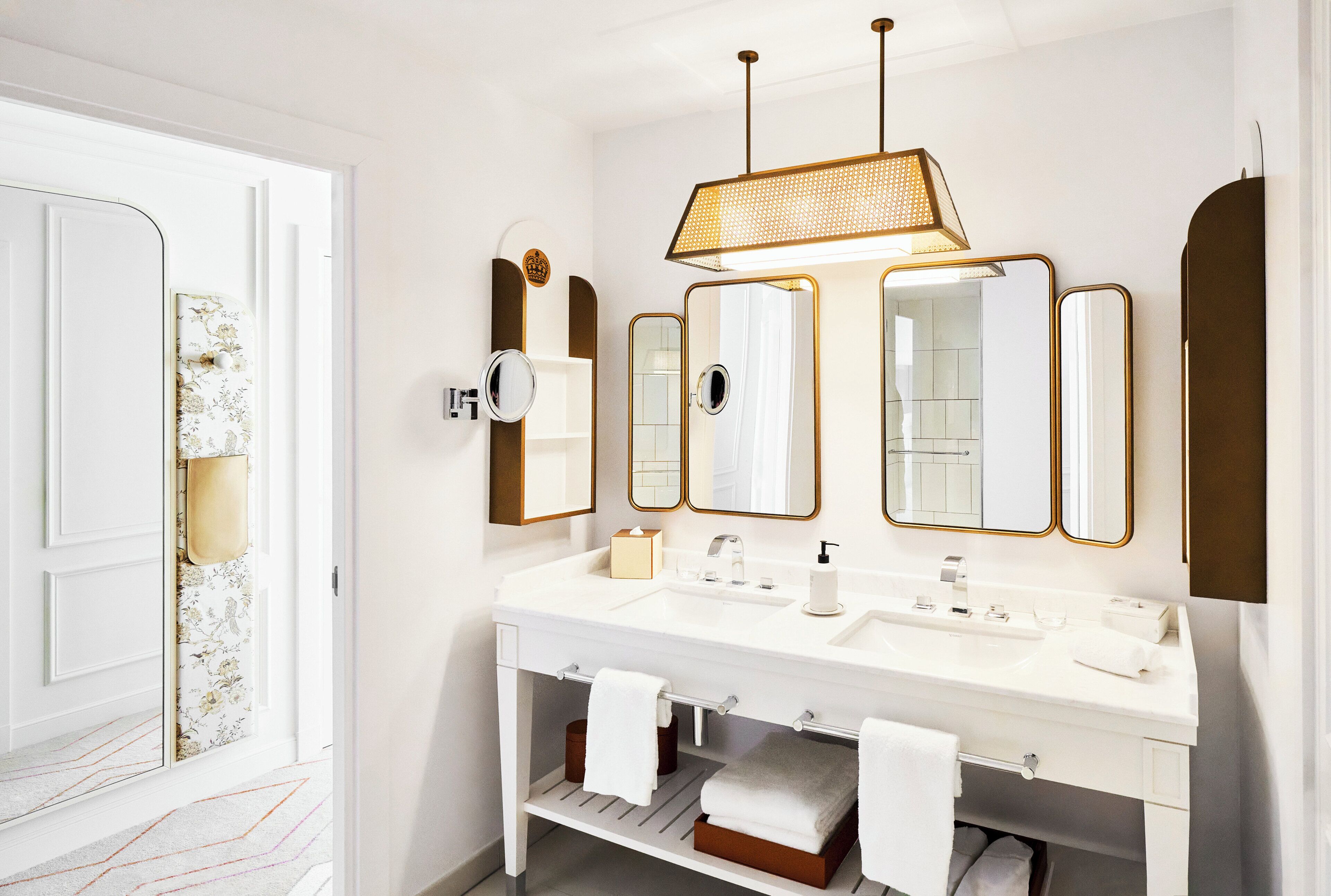 A modern bathroom with a white vanity, multiple mirrors, and a hanging light fixture.