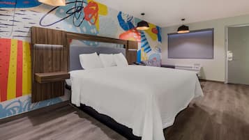 A modern hotel room with a large bed, wooden headboard, and a colorful abstract mural on the wall.