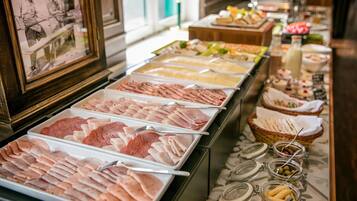 A buffet with various food options including meats, cheeses, and fruits.