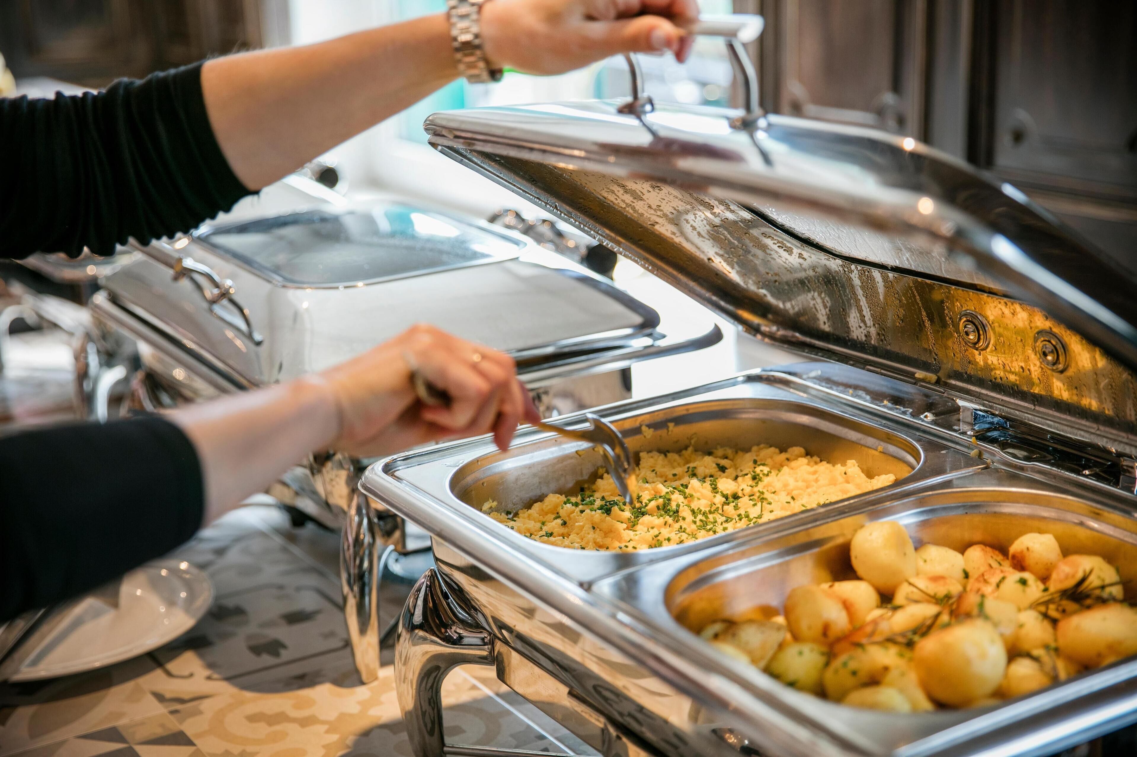 A buffet setup with various food items and utensils.