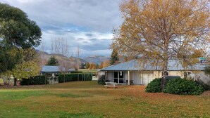 A residential area with houses, a grassy yard, and a mountain backdrop.