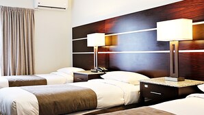 A hotel room with two beds, a wooden headboard, bedside tables with lamps, a nightstand, and an air conditioning unit. - Airport Gateway Hotel (Auckland)