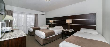 Habitación de hotel con dos camas, un escritorio, una lámpara y un televisor.
