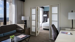 A hotel room with a sofa, a desk, a bed, and a view of the city.