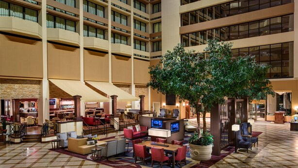 A spacious lobby with multiple seating areas, a central tree, and a bar.