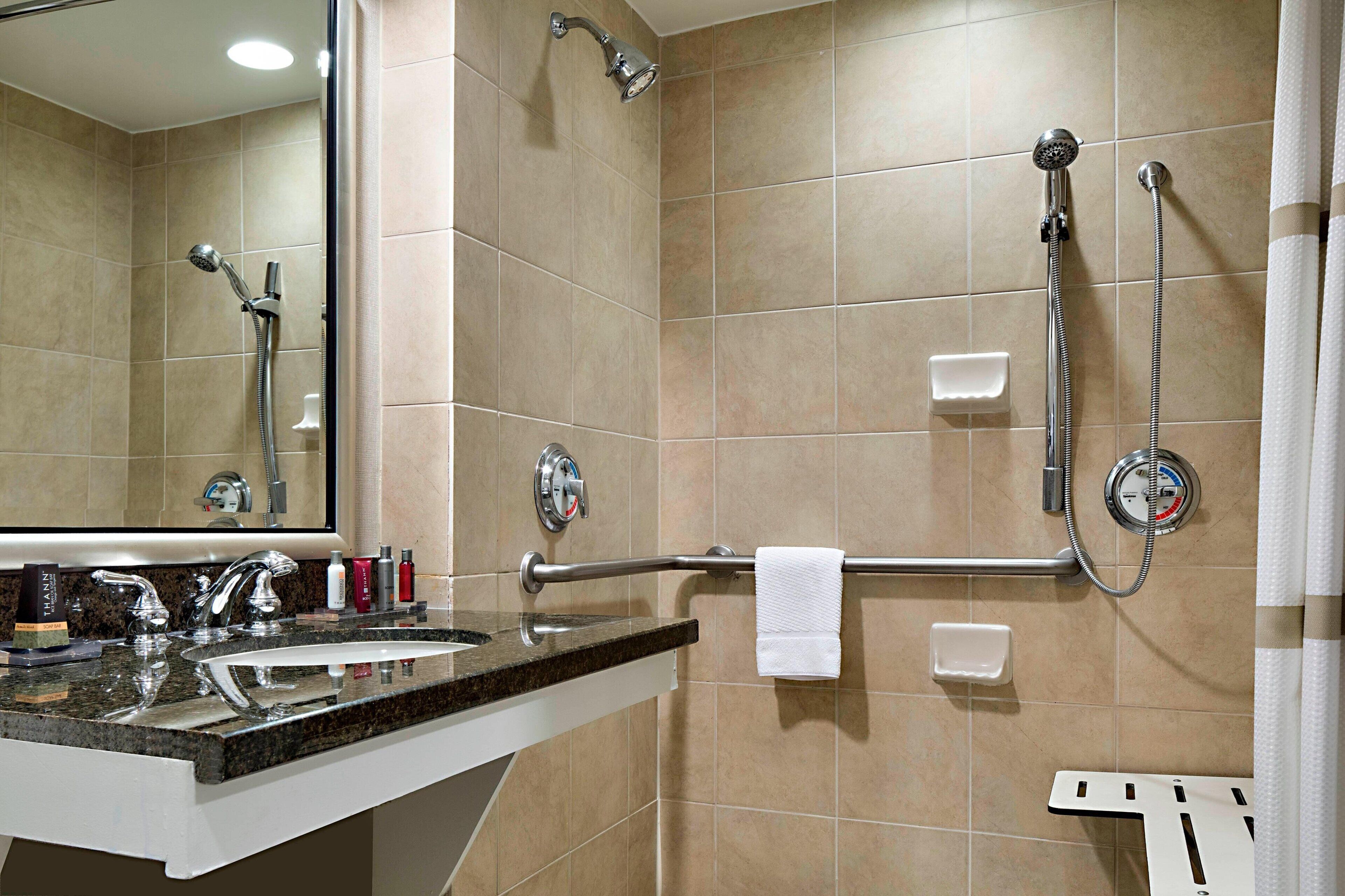 Une salle de bain équipée d’un lavabo, d’un miroir et de deux pommes de douche.