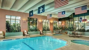 An indoor swimming pool with multiple lanes, surrounded by lounge chairs and tables, and decorated with American flags.