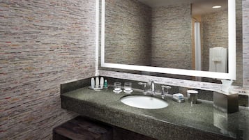 A bathroom with a granite countertop, a sink, a mirror, and a shower visible in the reflection.