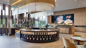 A modern coffee shop with a central counter, shelves of coffee beans, and a large floral mural on the wall. - Omni Atlanta Hotel at Centennial Park (Atlanta)