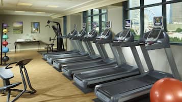 Un gimnasio con cintas de correr, pelotas de ejercicio y una máquina de remo.