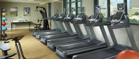 A gym with treadmills, exercise balls, and a rowing machine.