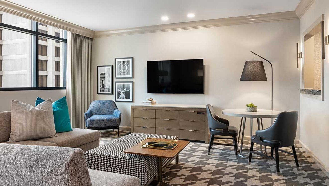 A modern living room with a sofa, armchair, and a small dining table.