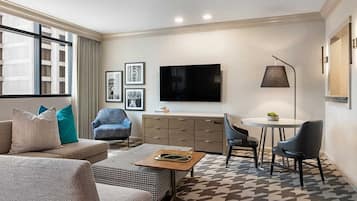 A modern living room with a sofa, armchair, and a small dining table.