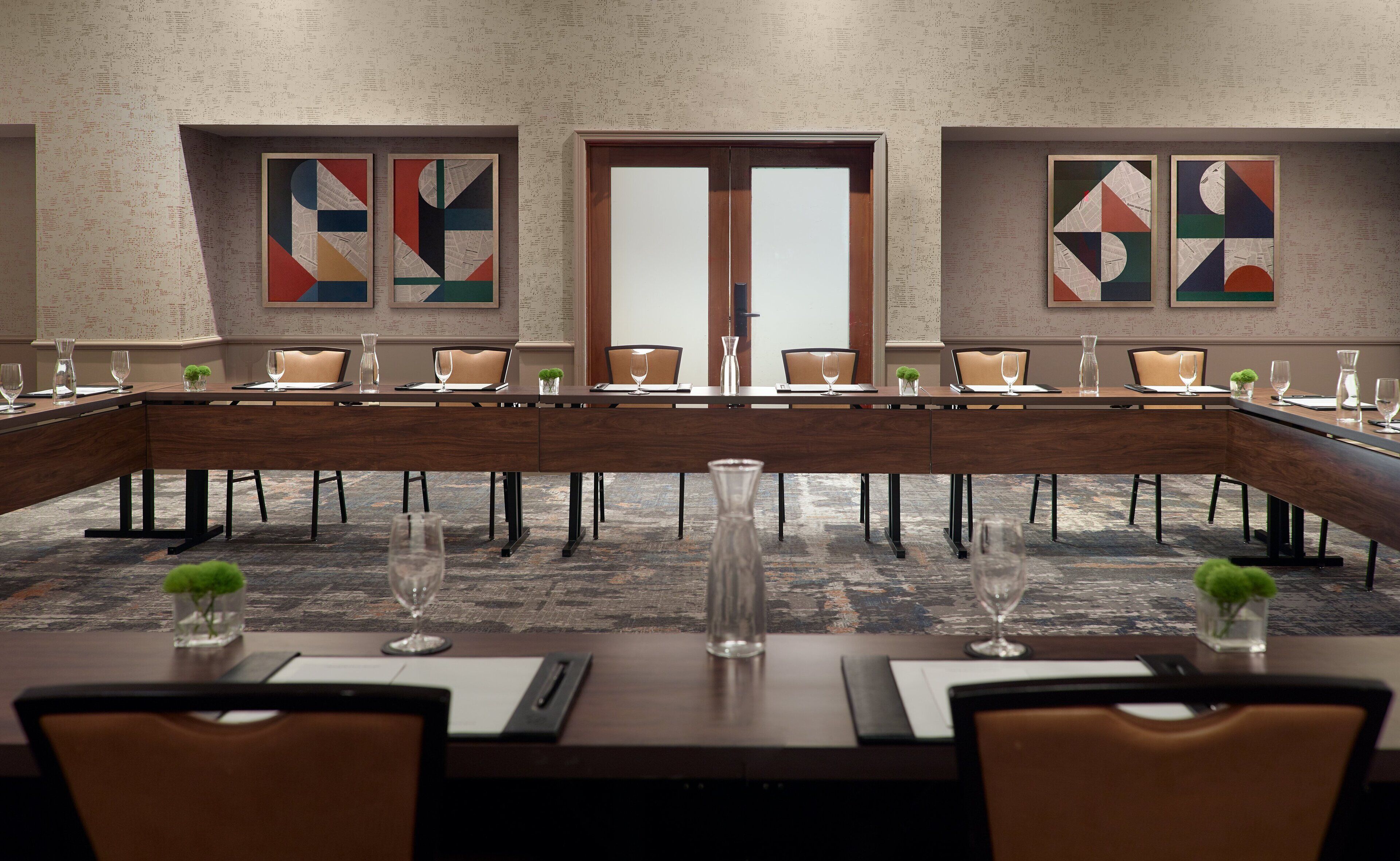 A conference room with a long table, chairs, and abstract art on the walls.