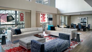 A spacious living room with a large window, a dining area, and a view of the city skyline.