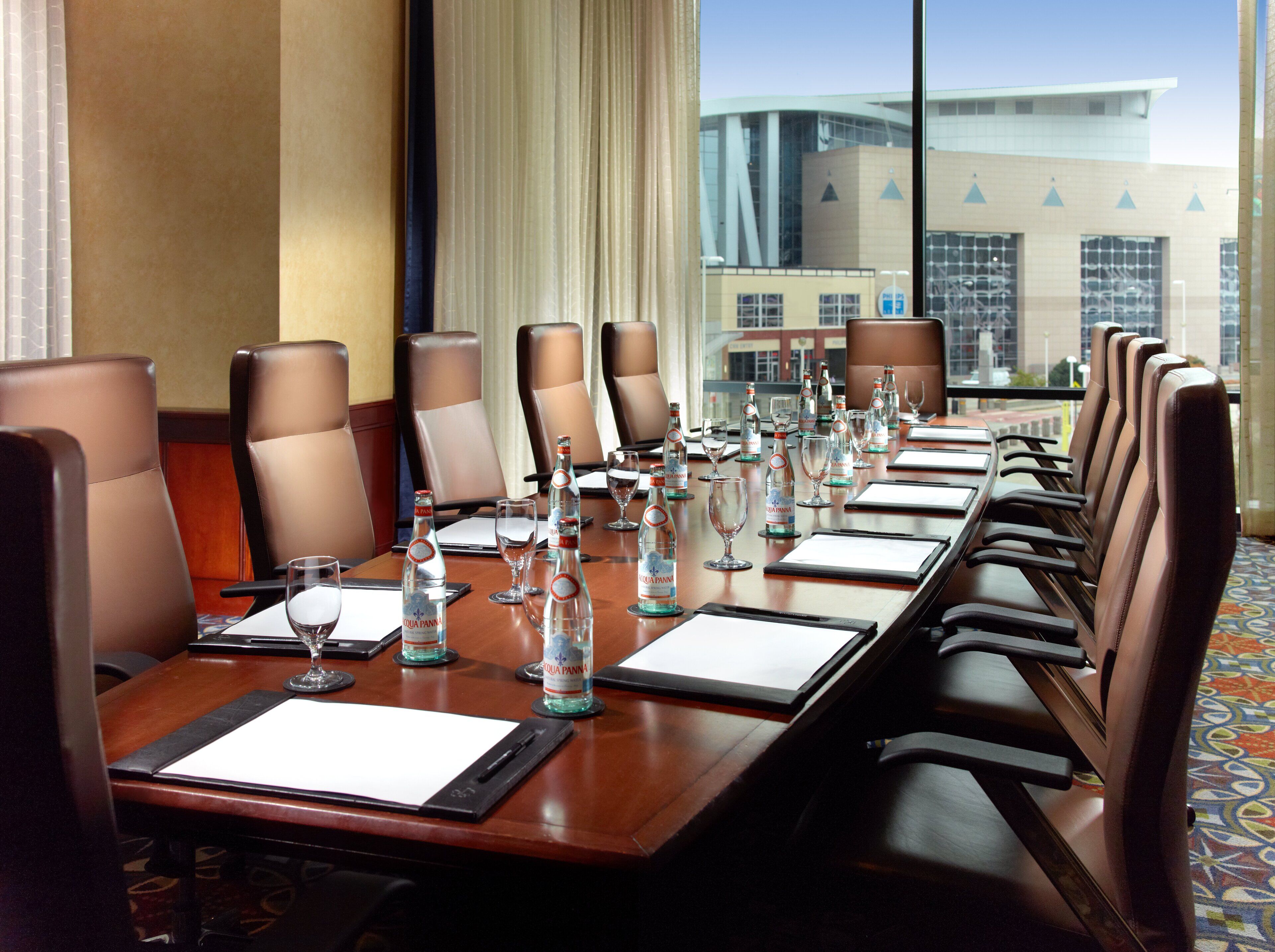 A conference room with a long table, brown leather chairs, water bottles, and glasses.