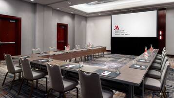 A conference room with a long table, multiple chairs, and a presentation screen.