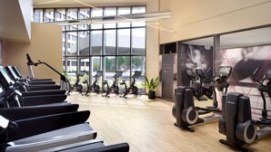 Une salle de sport moderne équipée de plusieurs tapis de course, de vélos d’appartement et d’appareils elliptiques.