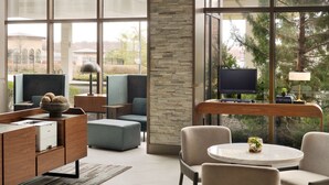 Un salon moderne avec un mur d’accent en pierre, un téléviseur à écran plat, des sièges confortables et une vue sur l’extérieur.