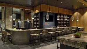 Un espace bar moderne doté d’un comptoir incurvé, de tabourets de bar et d’un grand écran de télévision.