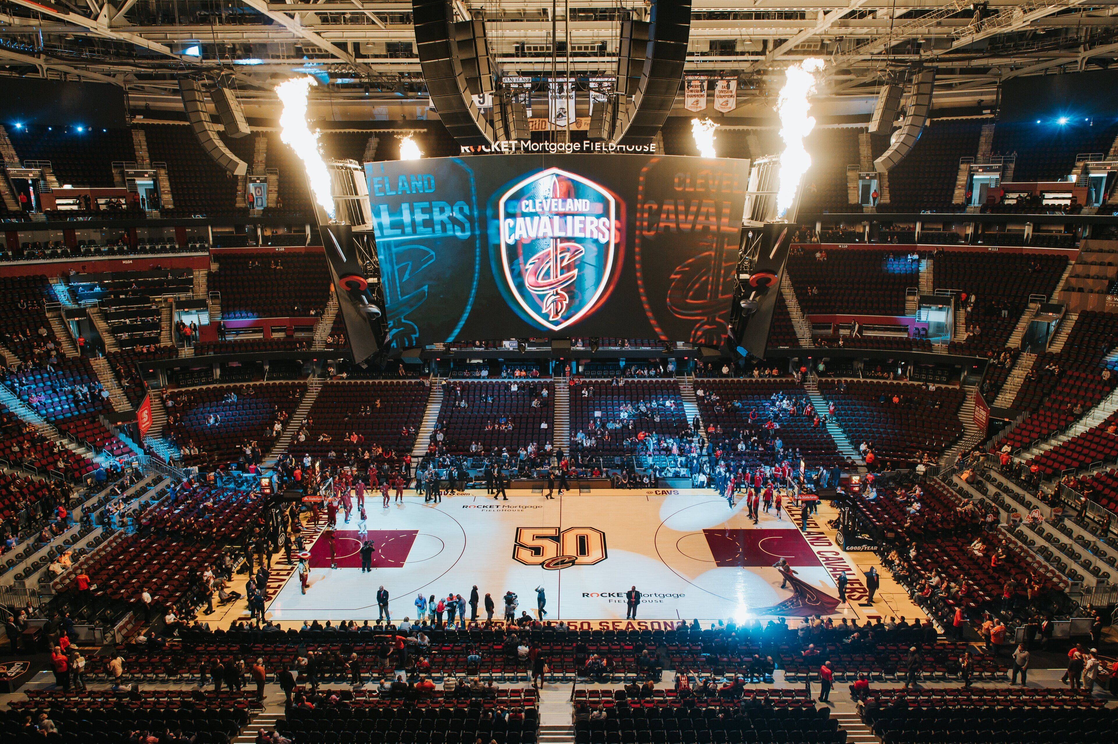 A basketball court with a large scoreboard displaying team logos and the number 50.