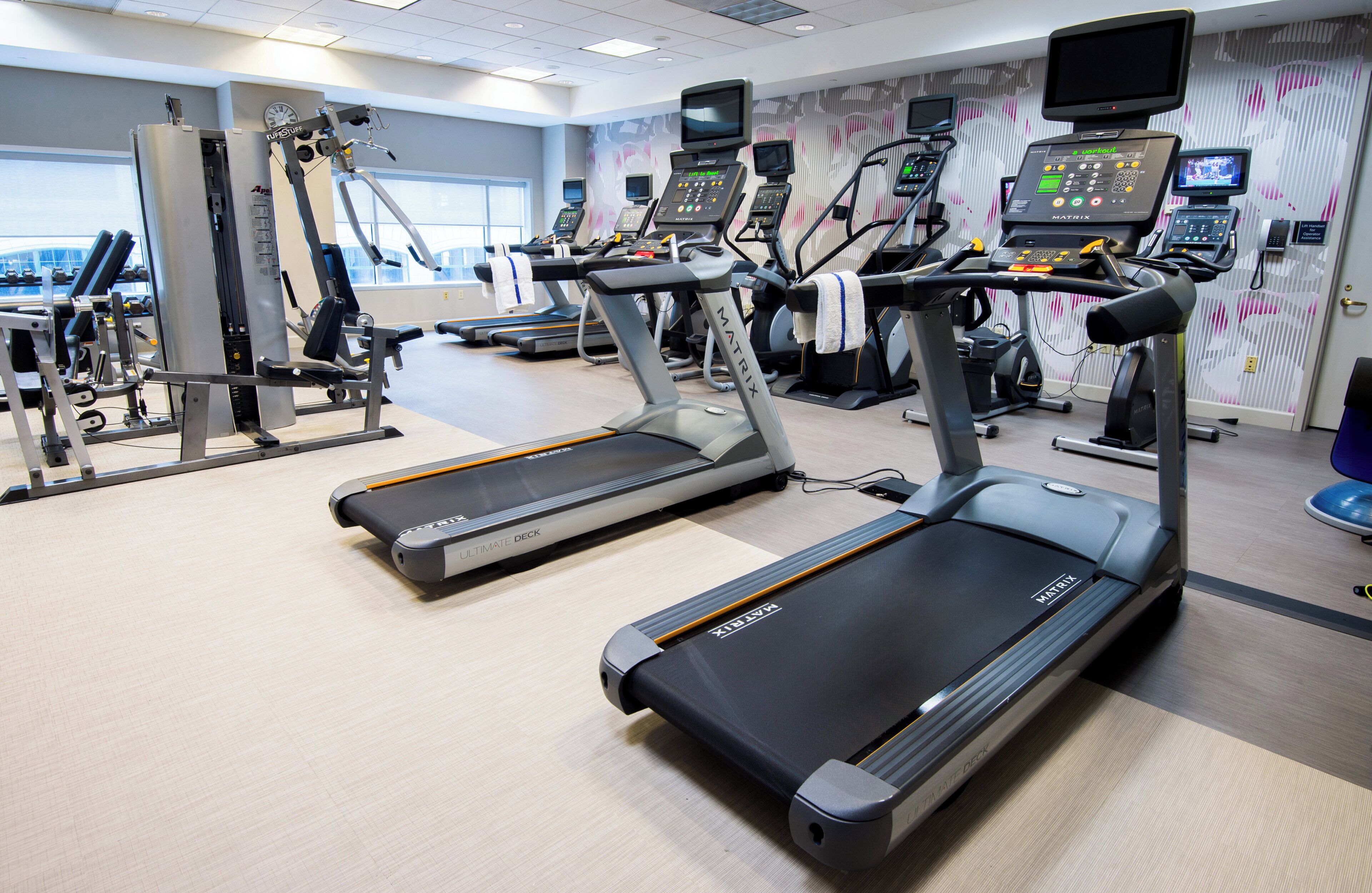Une salle de sport équipée de tapis de course, d’appareils de musculation et de moniteurs d’activité physique.