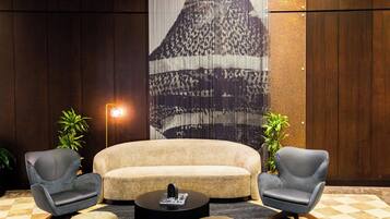 A modern lounge area with a sofa, two armchairs, a coffee table, and a patterned wall.