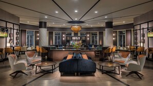 Un moderno vestíbulo de hotel con zona de bar, asientos y grandes ventanales.