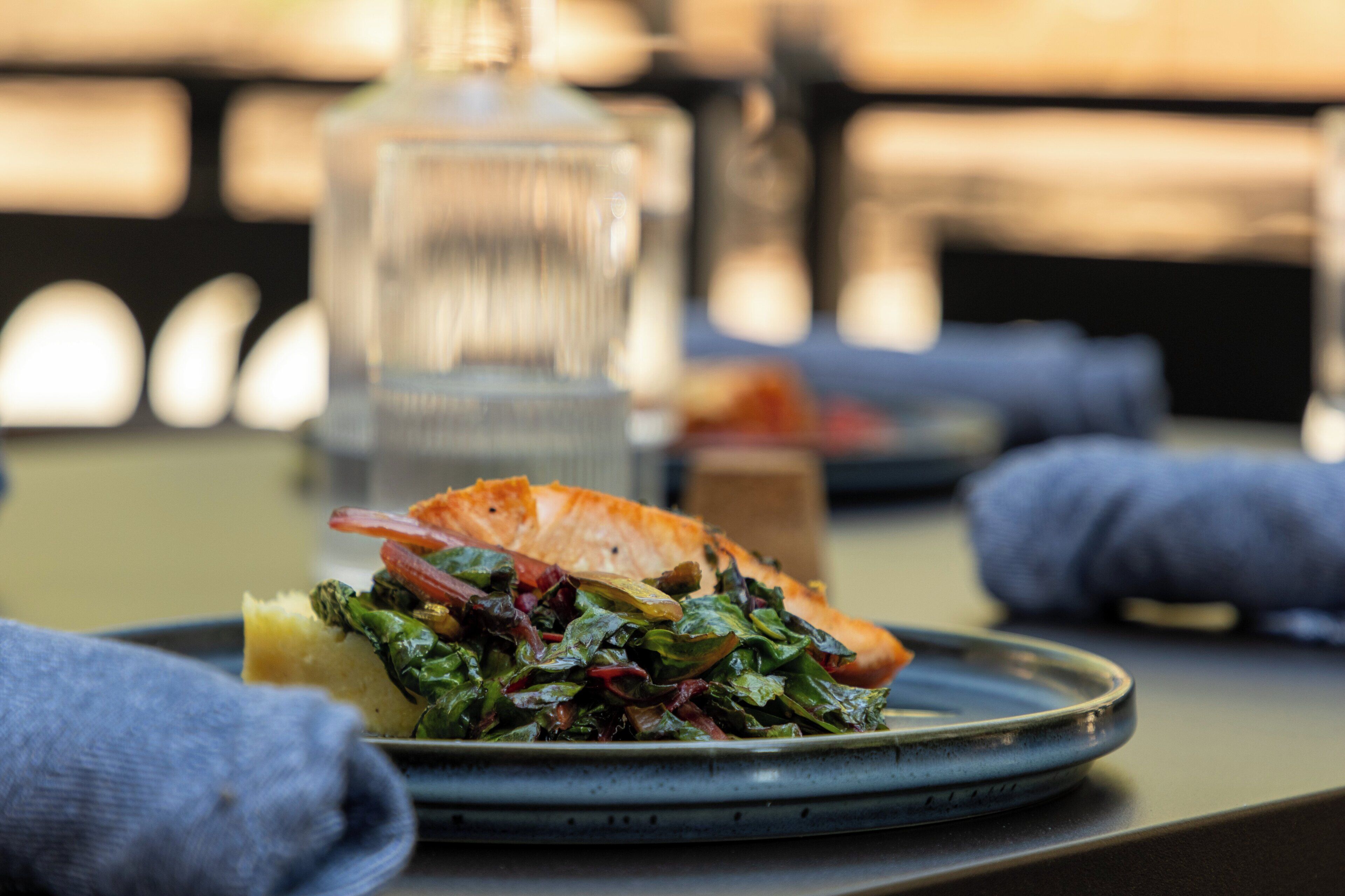 Une assiette de nourriture contenant du saumon et des légumes verts, posée sur une table.