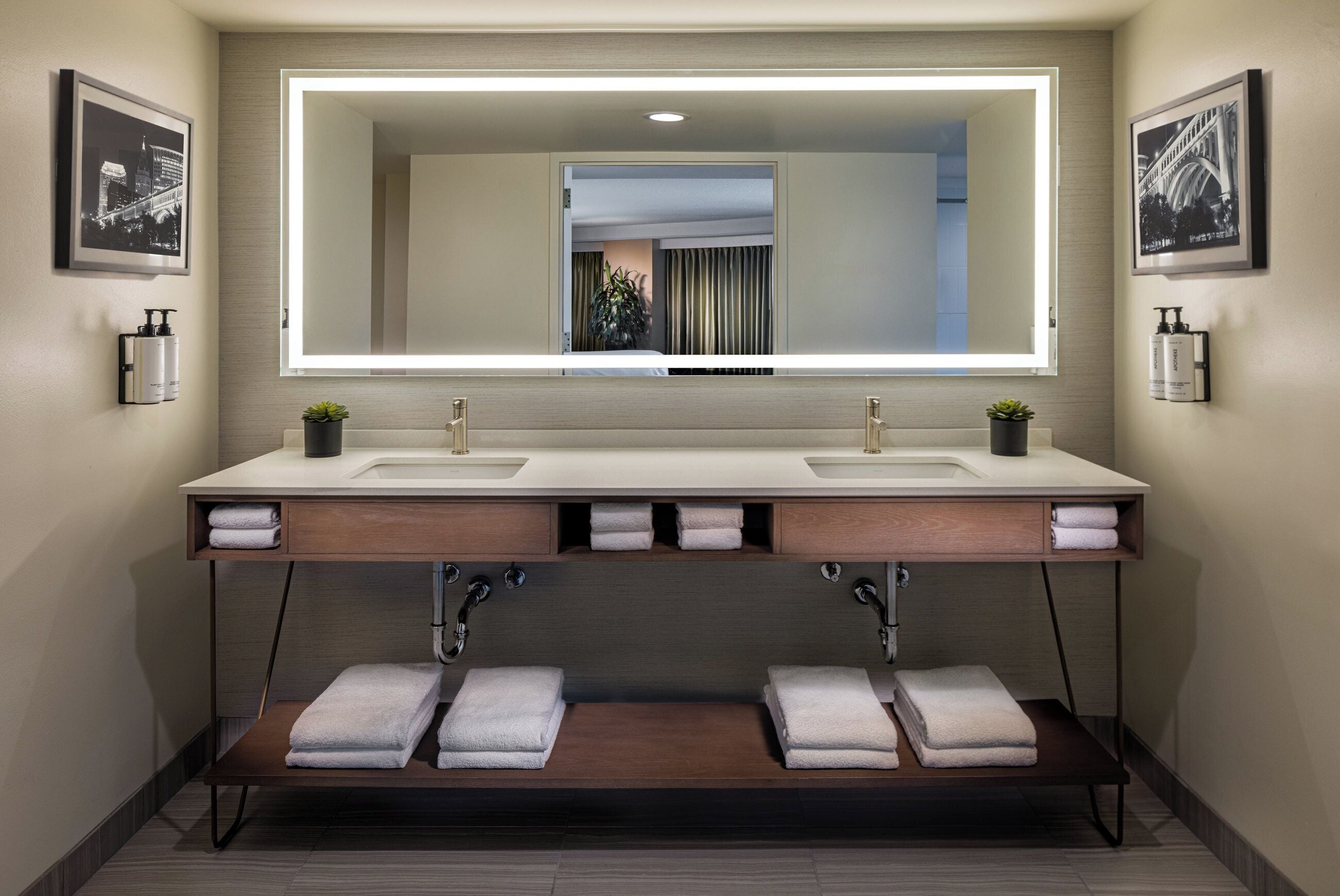 A modern bathroom with two sinks, a large mirror, and a towel rack.