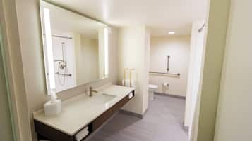 A modern bathroom with a large mirror, two sinks, a toilet, and a shower.