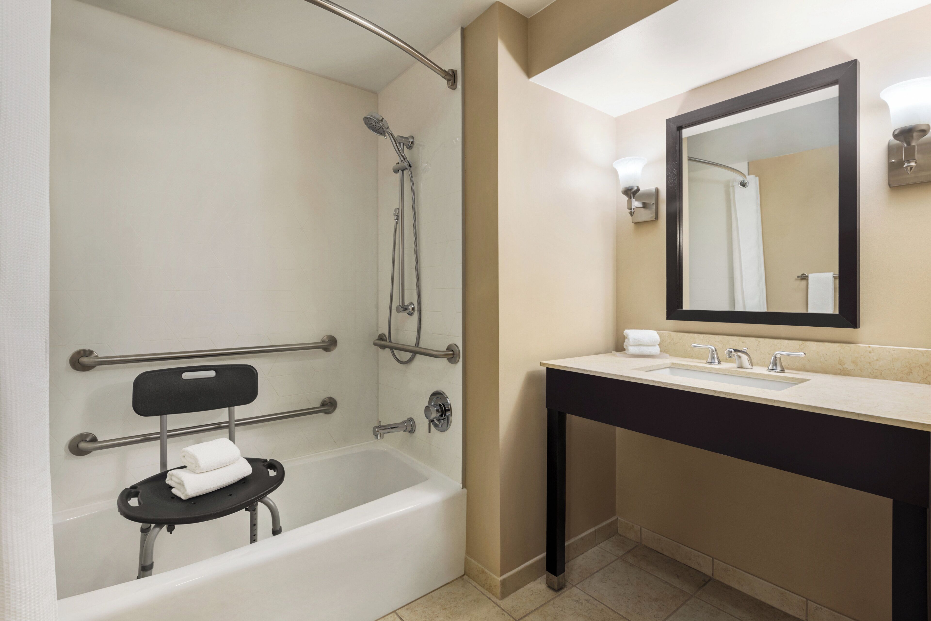 A modern bathroom with a bathtub, shower, and a vanity with a mirror.