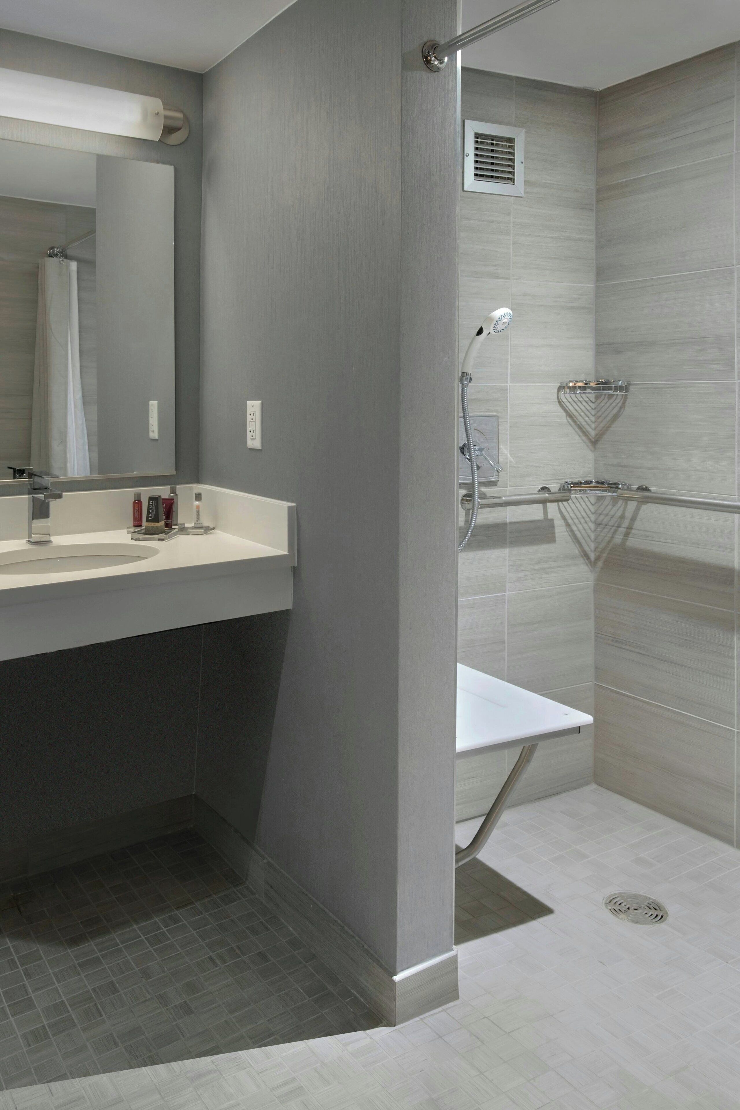 A modern bathroom with a large mirror, a sink, and a shower area.