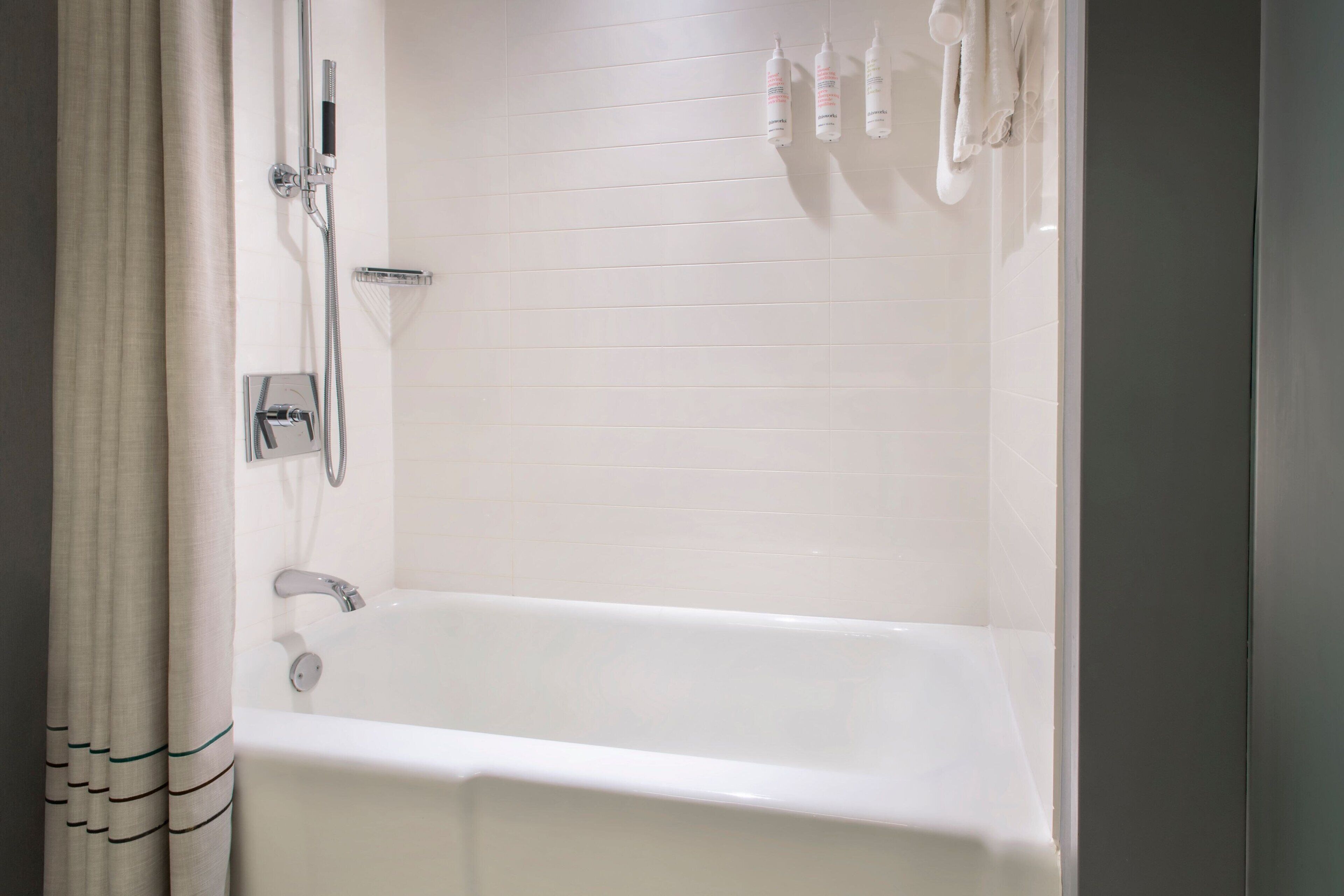 A bathroom with a bathtub, a shower, and a towel rack with towels.