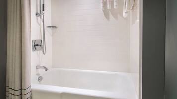 A bathroom with a bathtub, a shower, and a towel rack with towels.