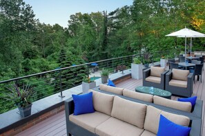 An outdoor patio area with a sofa set, a dining table, and a large umbrella.