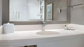 A modern bathroom with a large mirror, a round sink, and a glass shower enclosure.