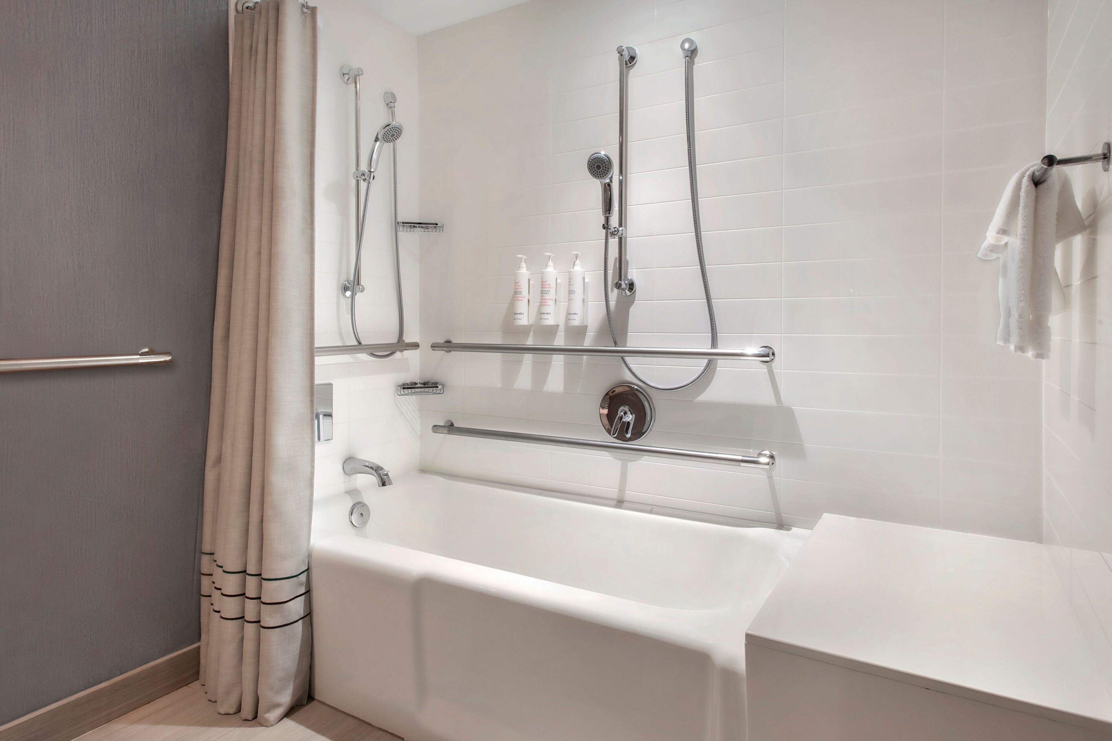 Un baño moderno con bañera, ducha y barras de apoyo.