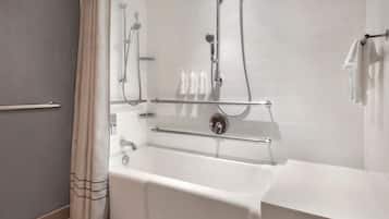 Un baño moderno con bañera, ducha y barras de apoyo.