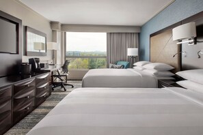 A hotel room with two beds, a desk with a chair, a television, and a large window offering a city view. - Boston Marriott Burlington (Burlington)