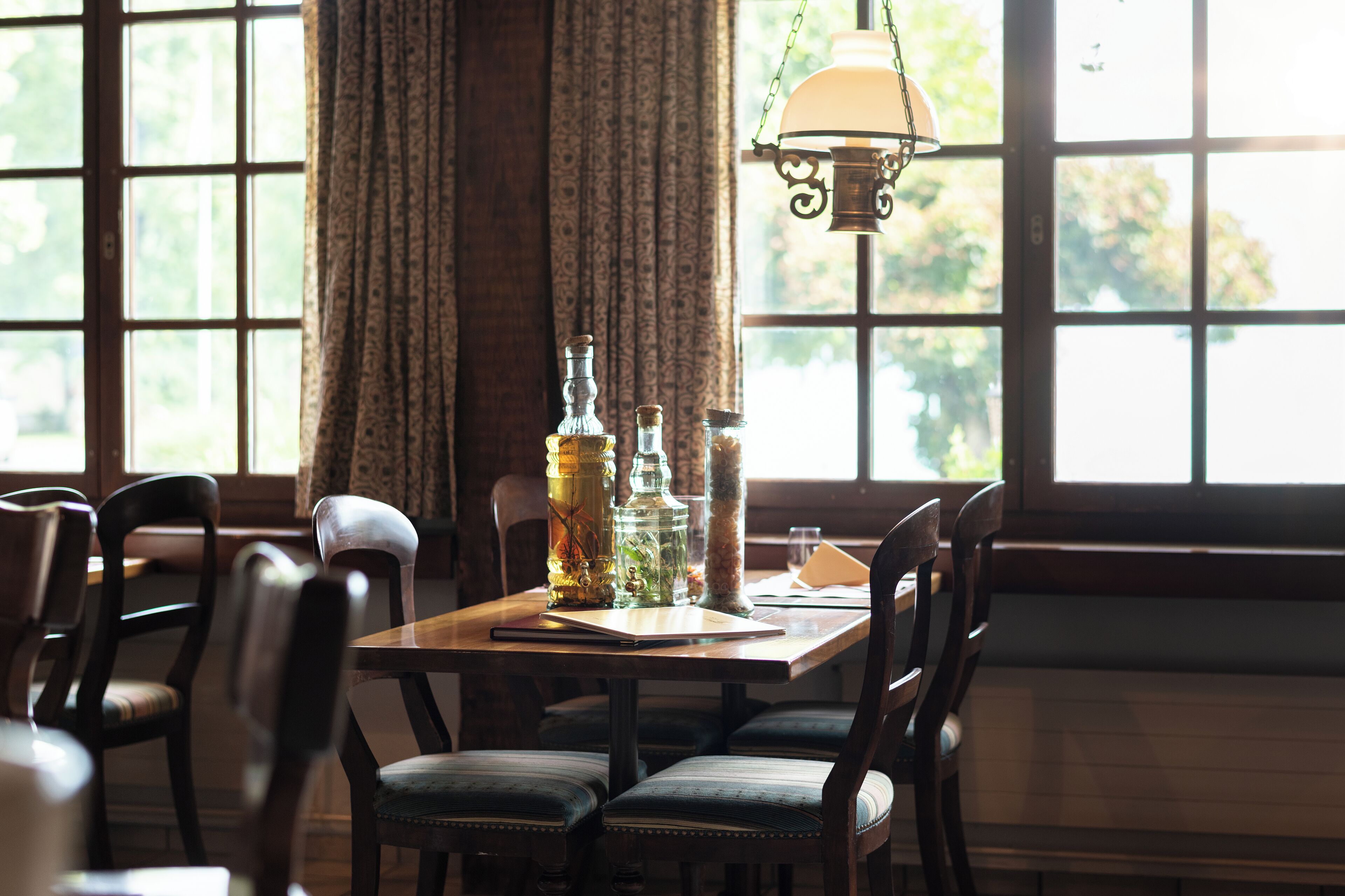 A dining area with a wooden table, chairs, and a hanging light fixture.